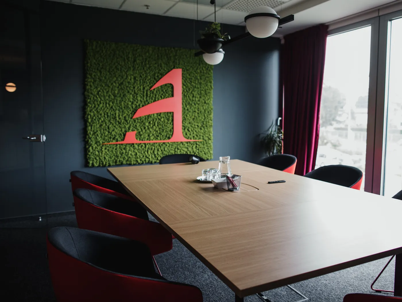 Sala za sastanke s velikim drvenim stolom i zelenim zidom s Arboninim monogramom